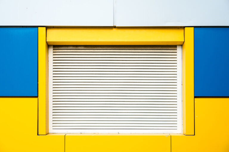 Un volet fermé sur un mur jaune et bleu