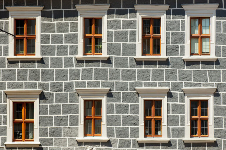 Plusieurs fenêtres en bois avec des linteaux sur un mur gris