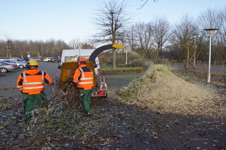 Des jardiniers utilisent un broyeur de végétaux pour leur travaux