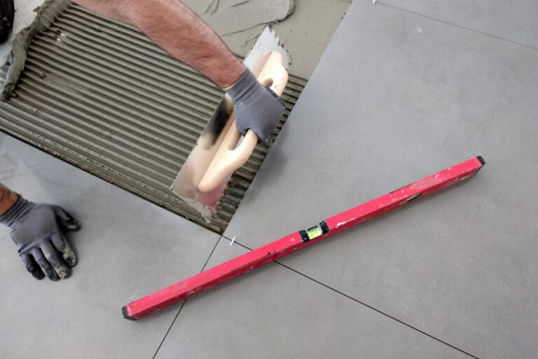 Un ouvrier qui rattrape le niveau du sol avec de la colle carrelage