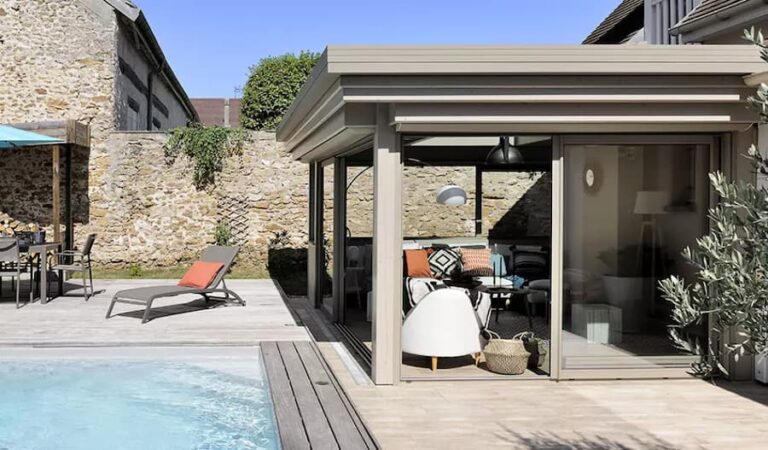 Extension de maison à toit plat reliant l’espace de vie à la piscine