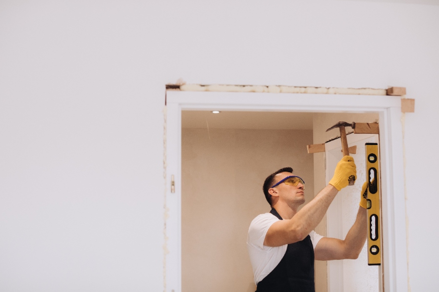 ne personne retire délicatement un cadre de porte en métal à l’aide d’outils