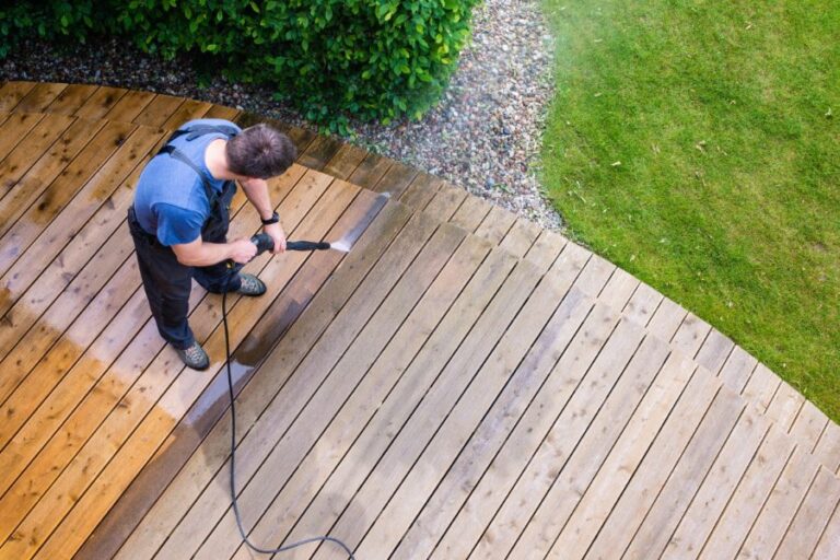 Homme appliquant une lasure protectrice sur des lames de bois, exemple concret de comment rénover facilement sa terrasse en bois