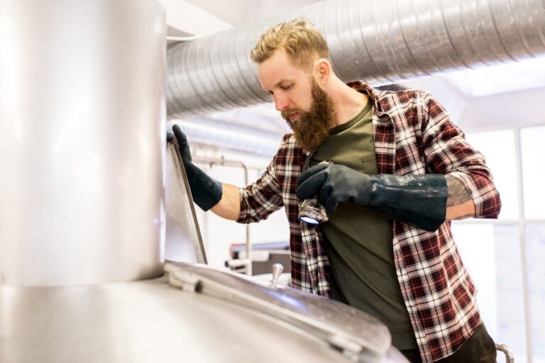 Artisan utilisant une perceuse pour réaliser un trou dans un mur destiné à l’installation d’une ventilation