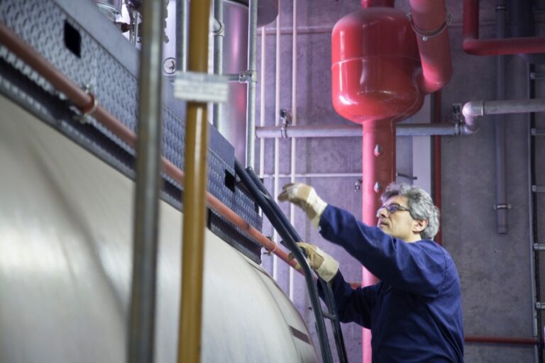 Une main ouvre le robinet de remplissage d’une chaudière Viessmann Vitodens 100 pour ajuster la pression