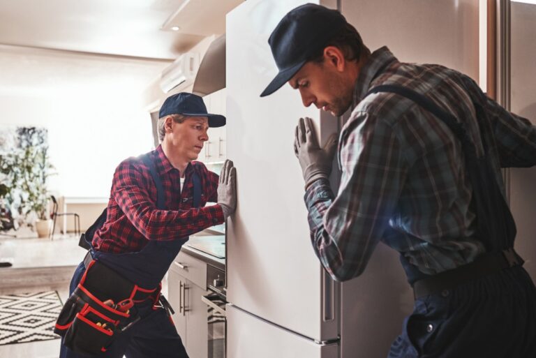 Des professionnels qui déplacent un grand réfrigérateur dans une maison