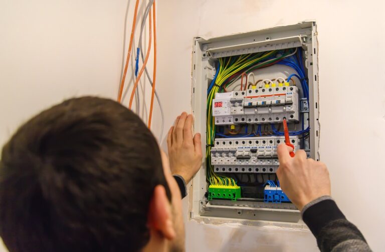 Un homme installant un panneau électrique avec un disjoncteur Legrand