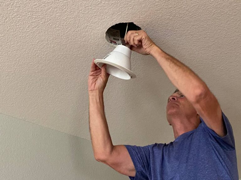 Un homme qui installe un luminaire au plafond