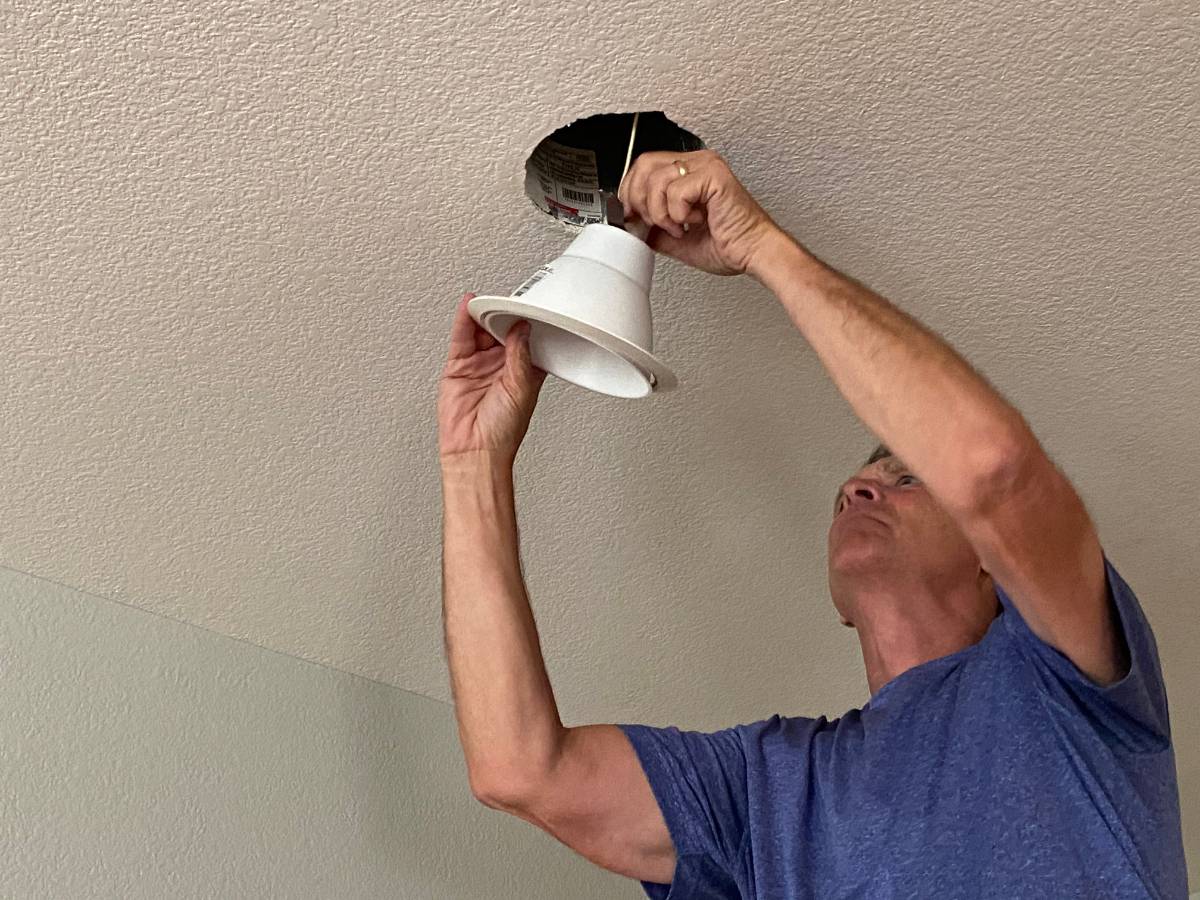 Un homme qui installe un luminaire au plafond