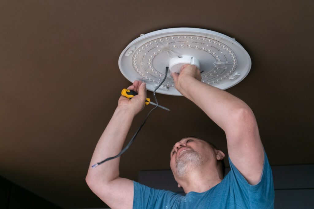 Un homme qui installe un nouveau luminaire