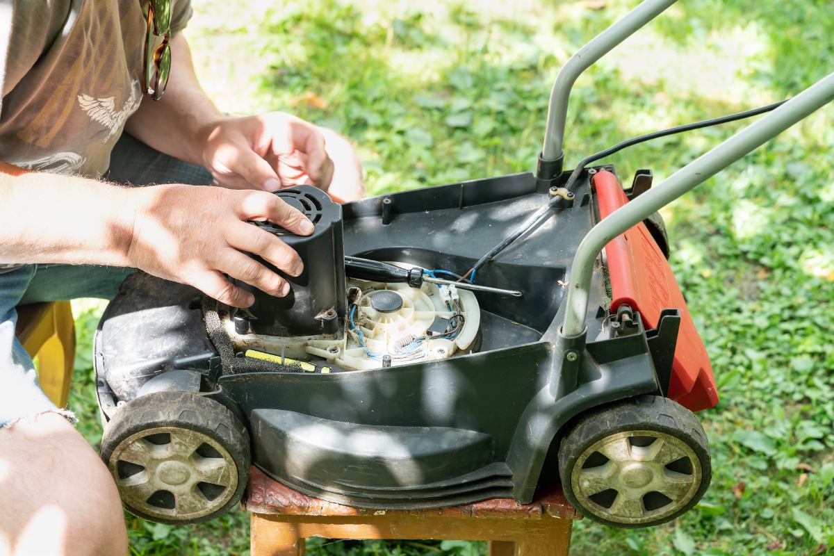 Un homme qui vérifie le bruit métallique du moteur de sa tondeuse