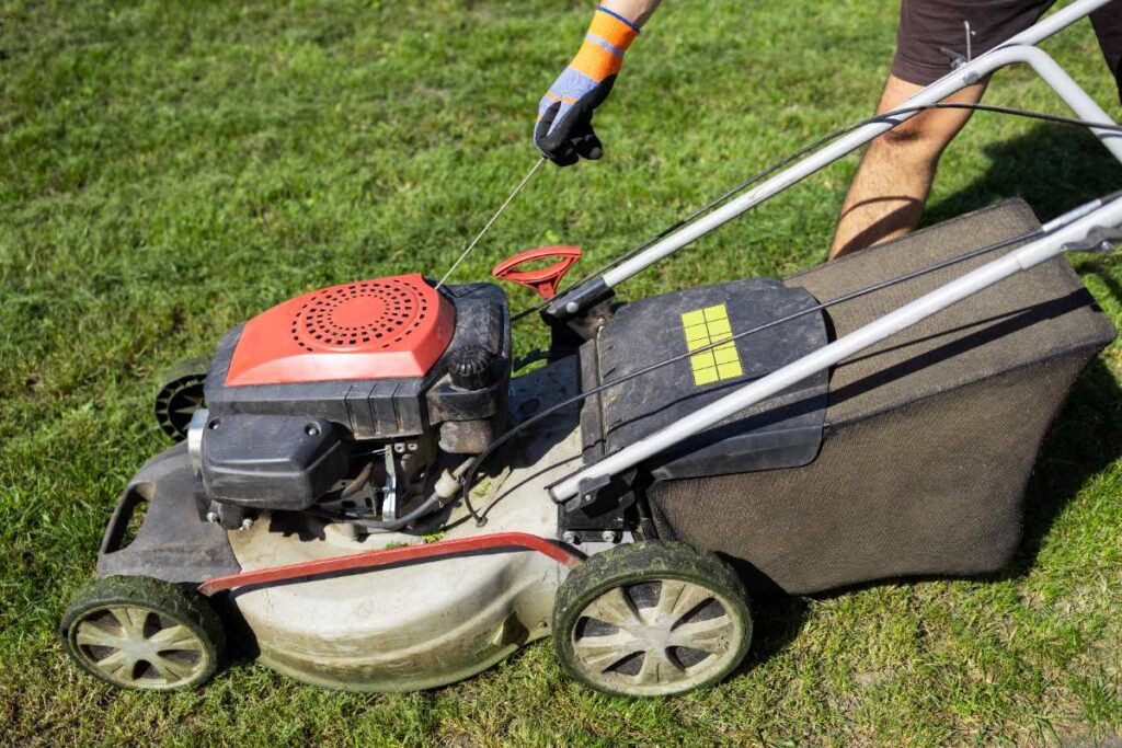 Un jardinier qui utilise une tondeuse au jardin et vérifie le buit du moteur