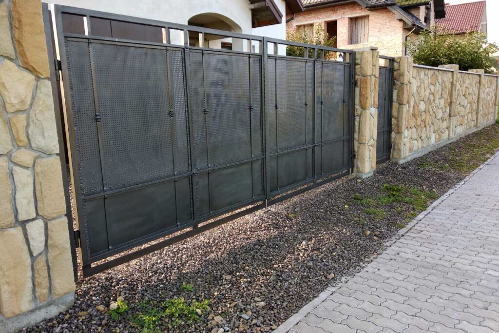 Un portail semi-ajouré installé entre une clôture en pierre