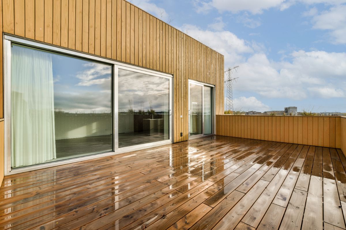 Une terrasse en bois devant une fenêtre en verre