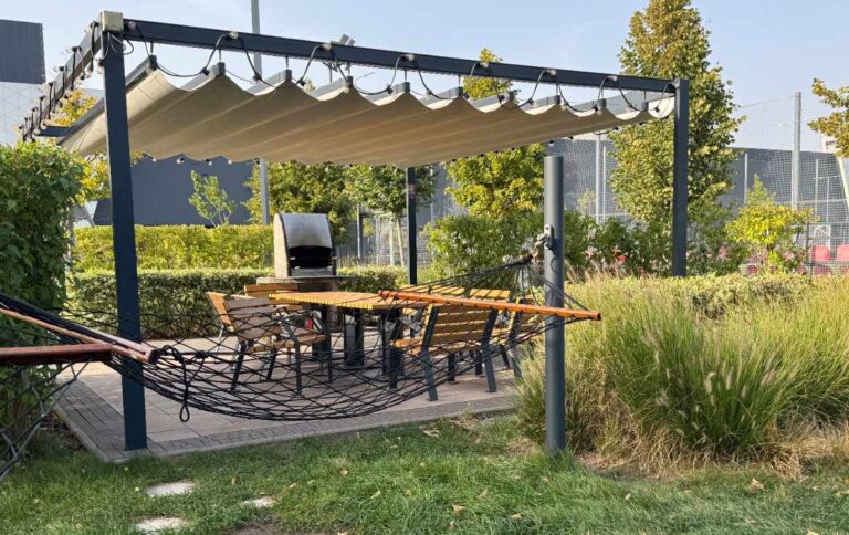 Une pergola dans le jardin avec un toit en bâche avec support en métal