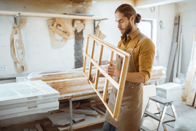 Un menuisier qui tient un cadre de fenêtre dans un atelier