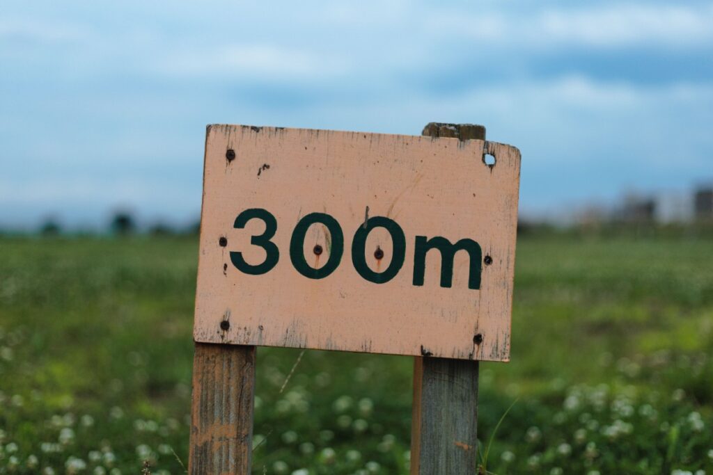 Un panneau avec un chiffre 300m écrit dessus, sur un terrain