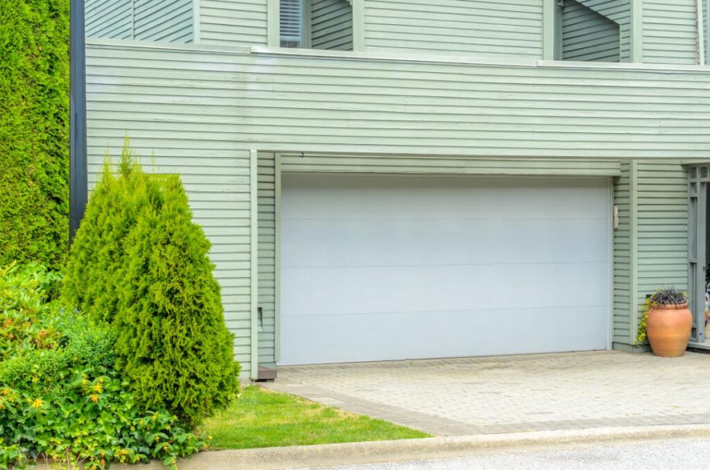 Une porte de garage installée près d'un jardin