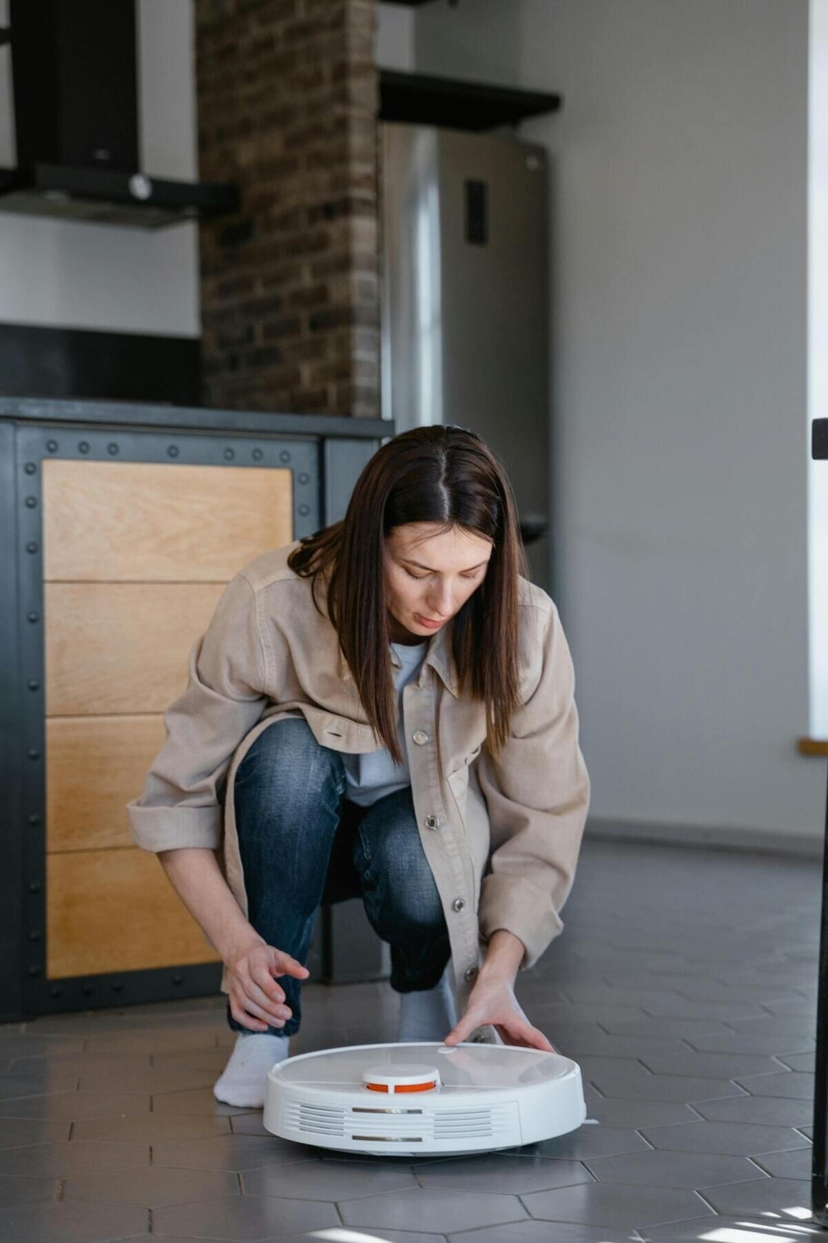 Femme nettoie avec son robot aspirateur dans sa maison