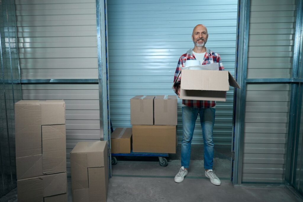 Un homme âgé qui déplace des cartons dans un box de stockage