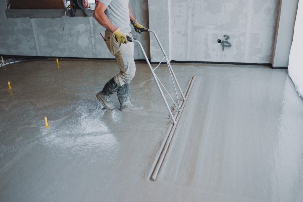 Un ouvrier qui lisse du béton dans une nouvelle maison