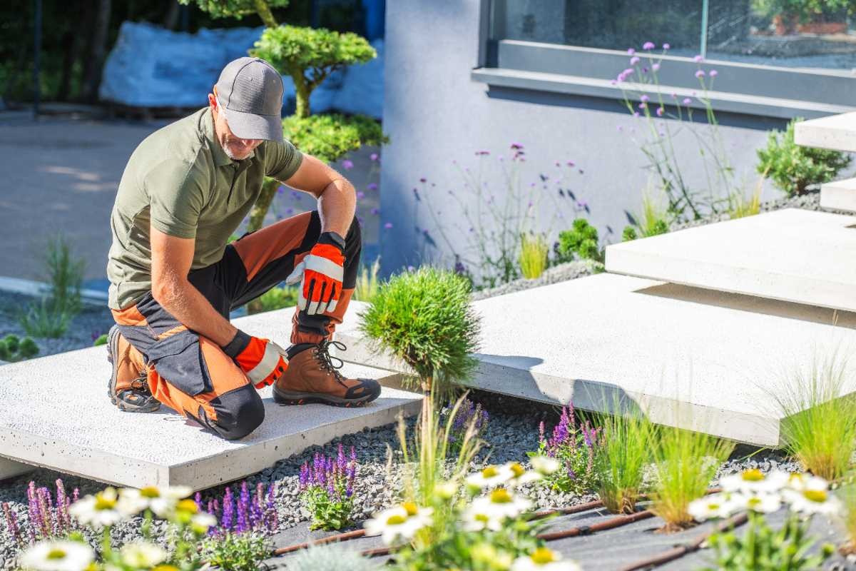 Un paysagiste qui regarde des fleurs dans le jardin