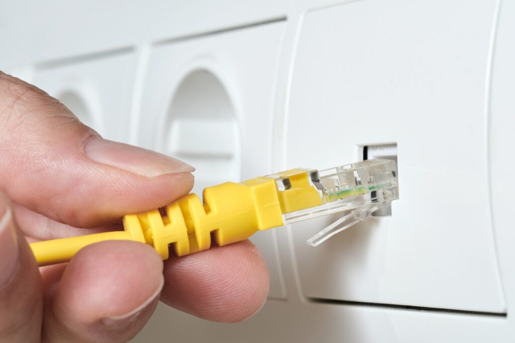 Une personne faisant brancher un câble internet jaune sur une prise RJ45