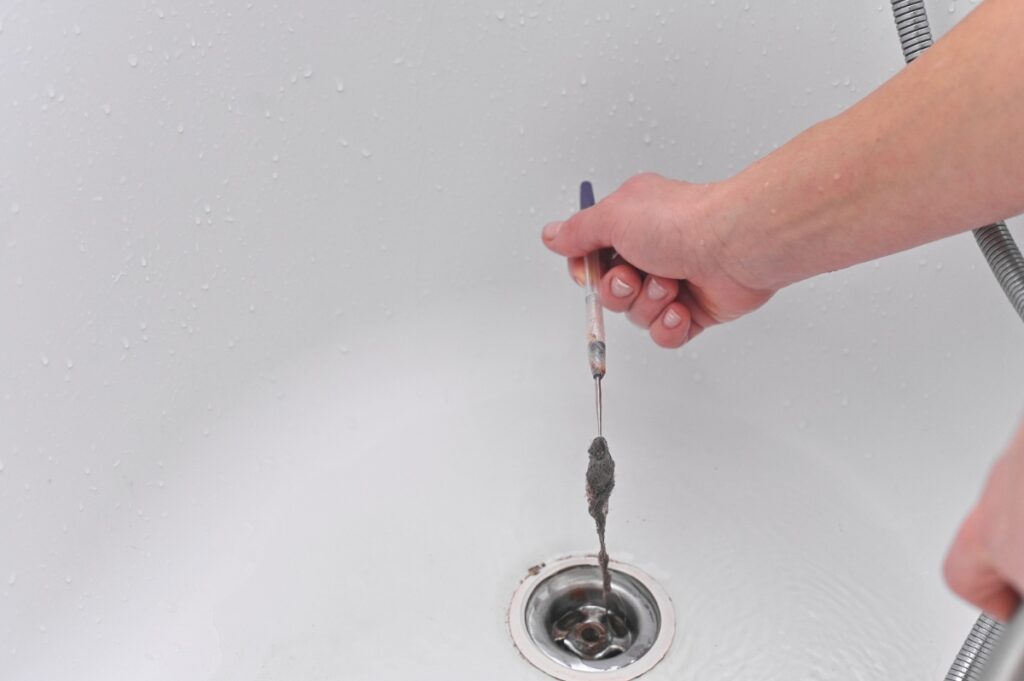 Une personne qui nettoie un drain avec un outil de retrait bouchon