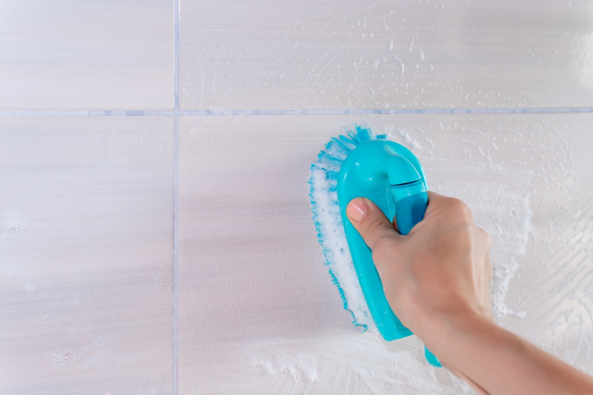 Une personne nettoyant un mur carrelé