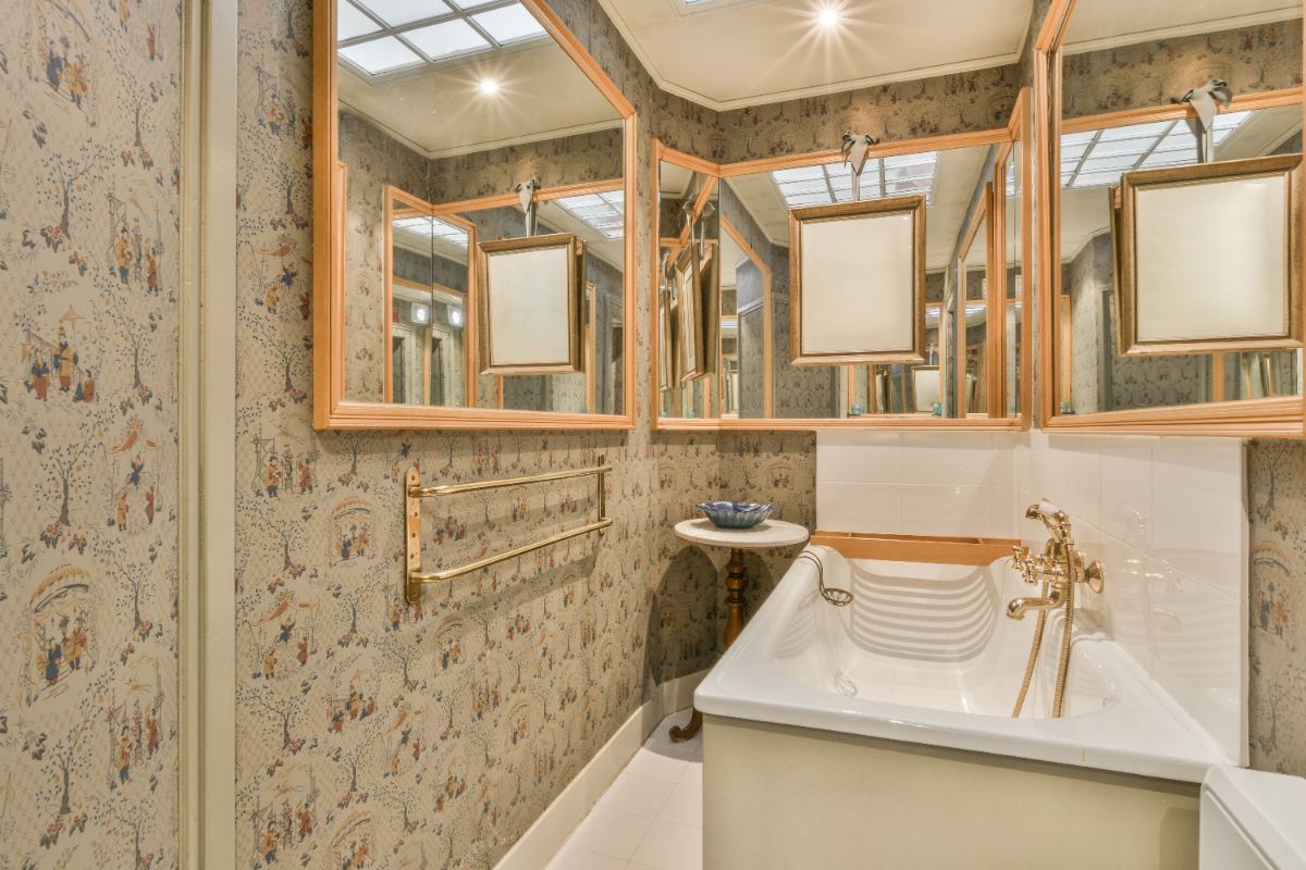 Une salle de bain avec un baignoire, des miroirs et du papier peint