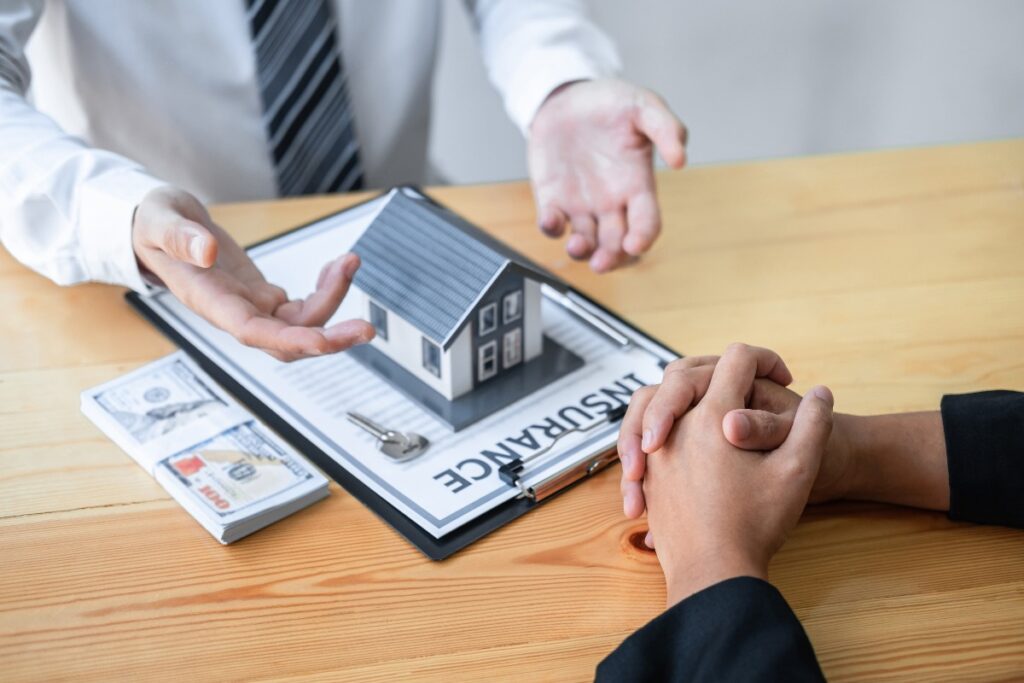 Un agent immobilier qui présente un contrat d'assurance habitation près des monnaies