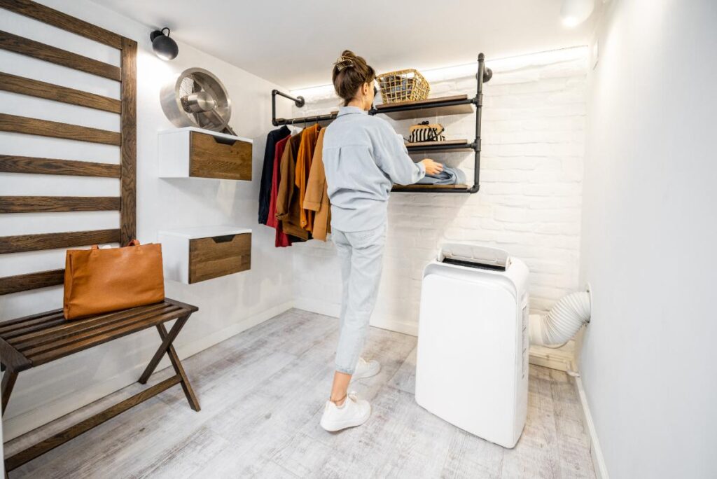 Une femme faisant du rangement dans une pièce avec un climatiseur mobile