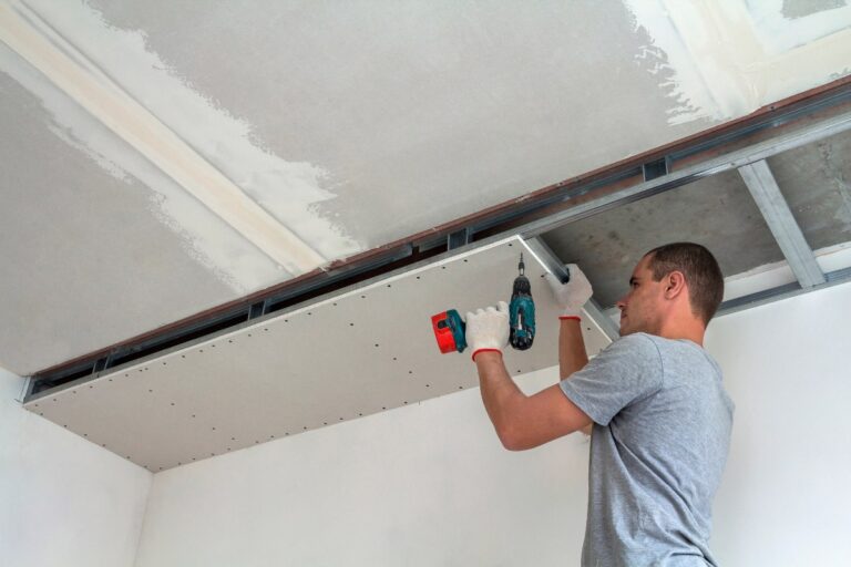 Un homme installant des plaques plâtres sur le plafond