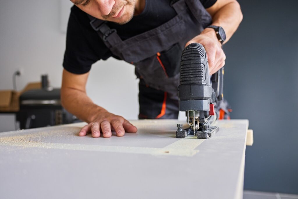 Un homme qui utilise une scie pour couper le placo
