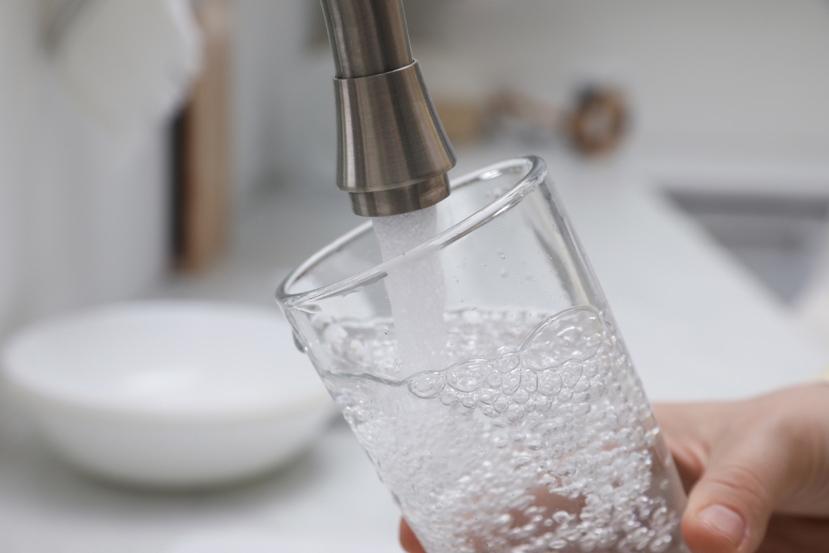 Une personne qui remplie un verre d'eau au robinet