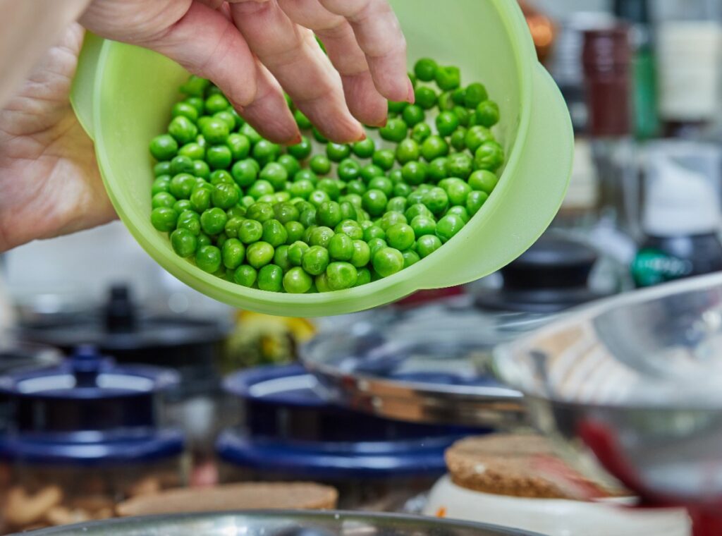 Une personne tenant un bol avec des petits pois