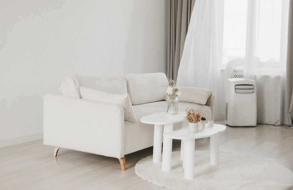 Un salon lumineux avec un canapé, une table basse et un climatiseur mobile