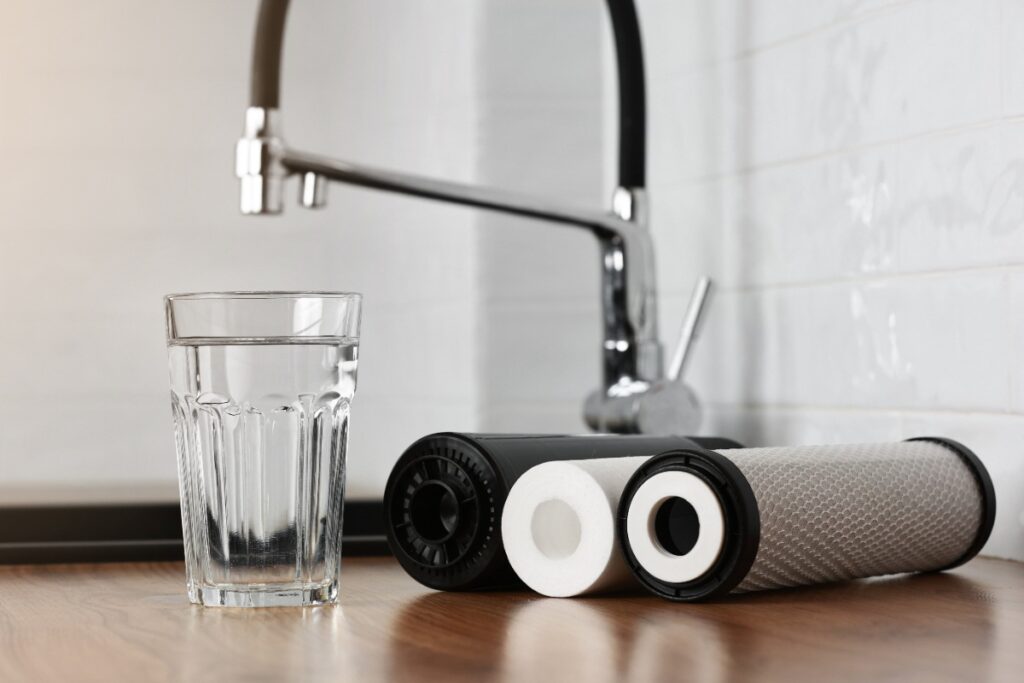 Un verre d'eau avec des filtres à eau près du robinet