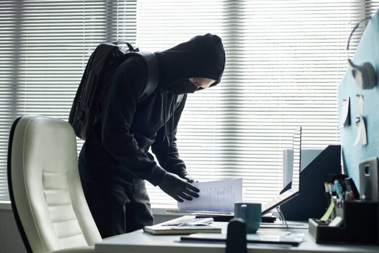 Un cambrioleur portant un masque et cherchant du document dans un bureau