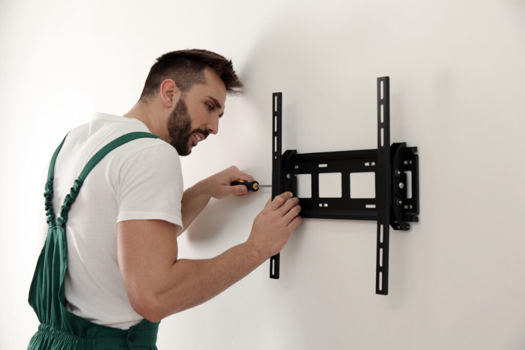 Un homme assemblant du support mural pour télévision