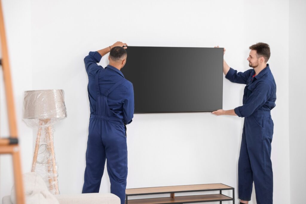 Des hommes installant une nouvelle télévision dans une chambre
