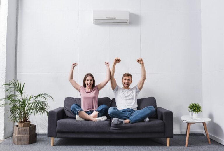 Un couple heureux levant les bras sur un canapé