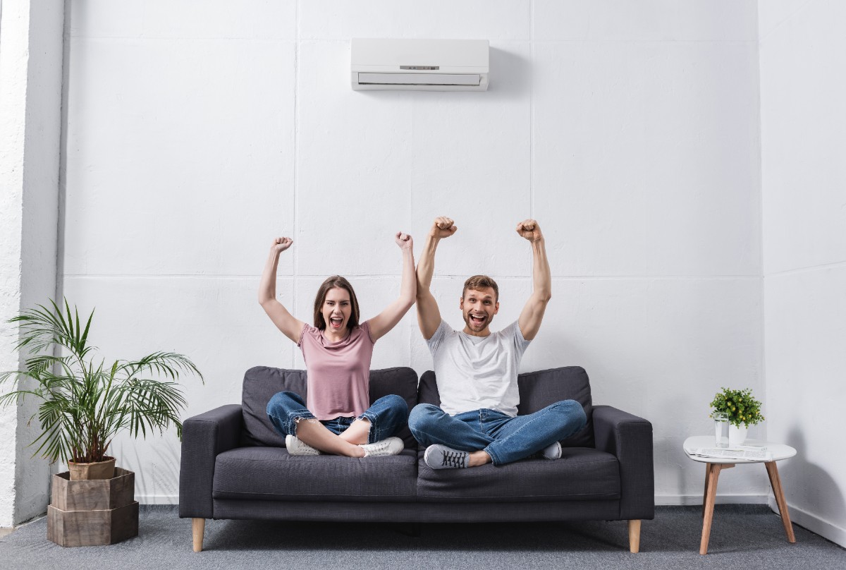 Un couple heureux levant les bras sur un canapé
