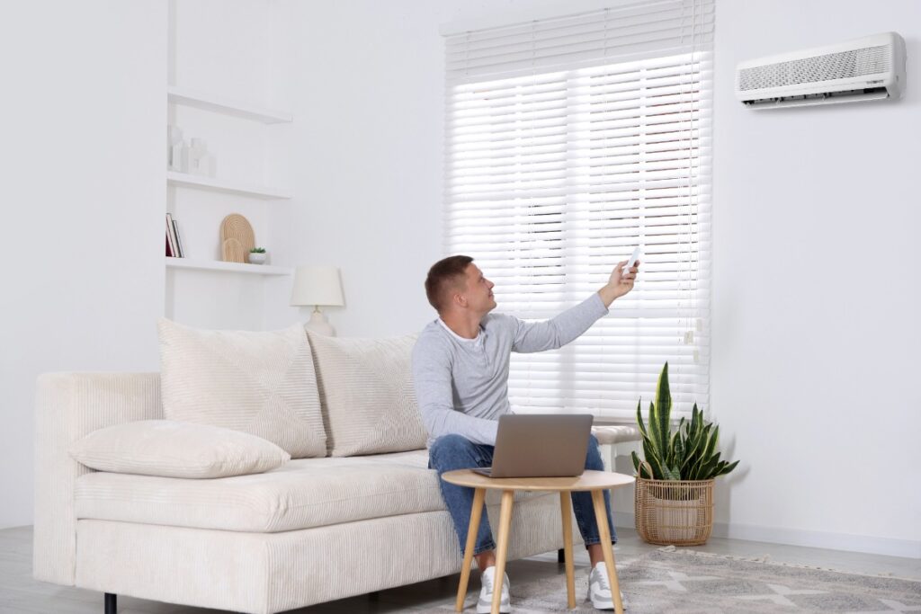 Un homme réglant la climatisation avec une télécommande