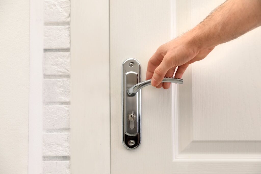 Main ouvrant une porte blanche