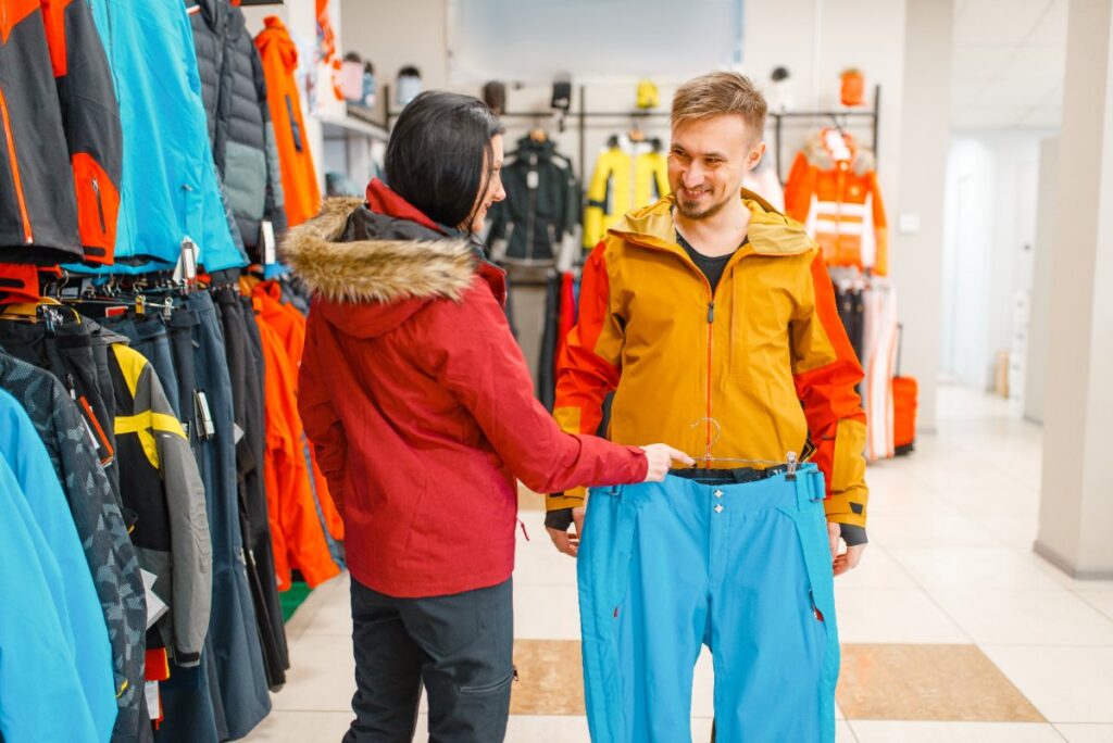 Une vendeuse qui aide un homme à choisir son pantalon anti-coupure dans un magasin