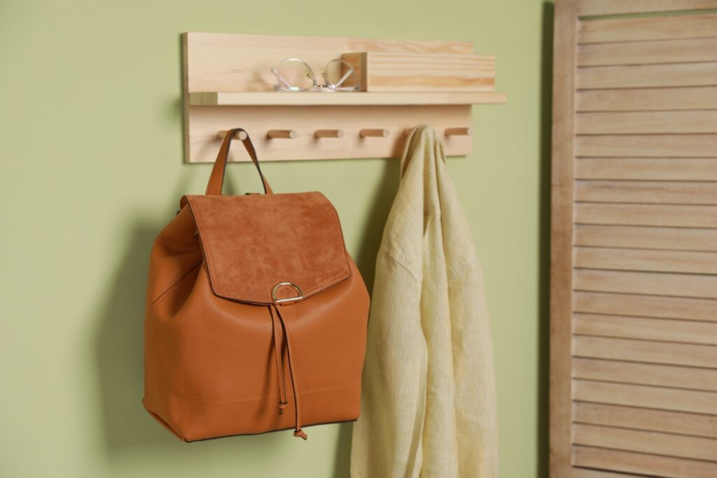 Un sac à dos beige et un manteau accrochés sur le mur