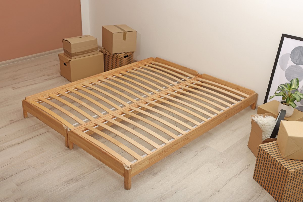 Un cadre de lit en bois avec des cartons dans une chambre