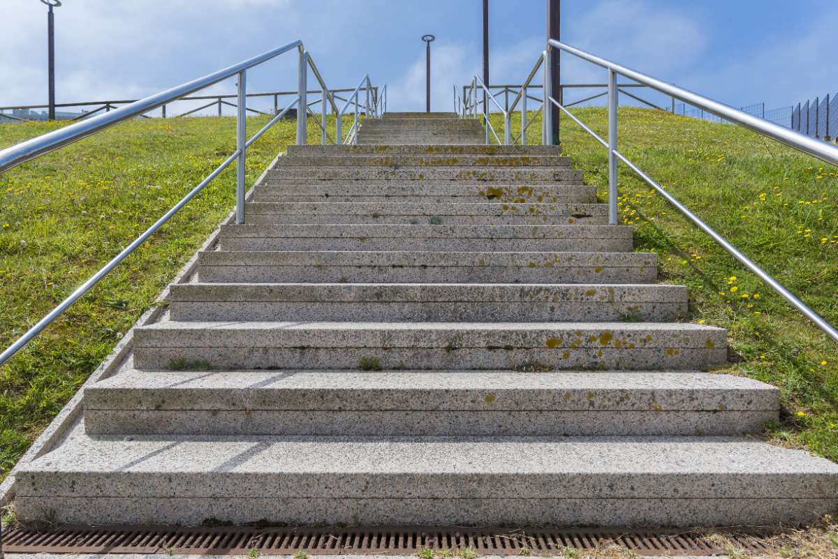 Un escalier en béton vers une colline herbeuse