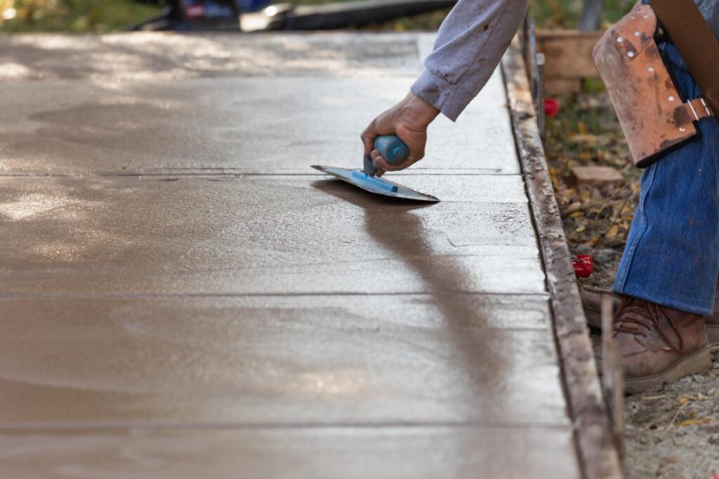 Un ouvrier lissant du ciment frais sur un chantier